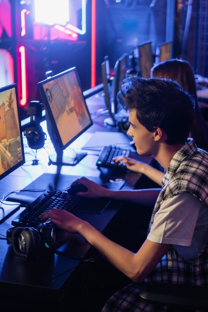 services-04 Two teenagers playing video games on computers in an esports arena setting.