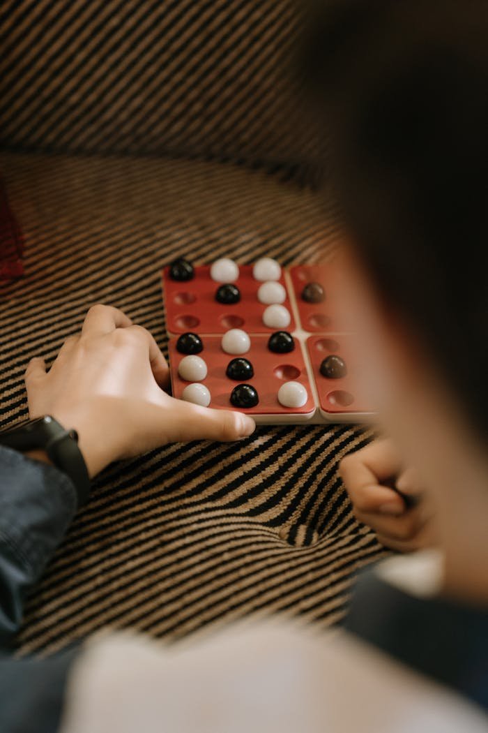 Close-up of hands strategizing in a Pentago game, showing intense focus on the board.